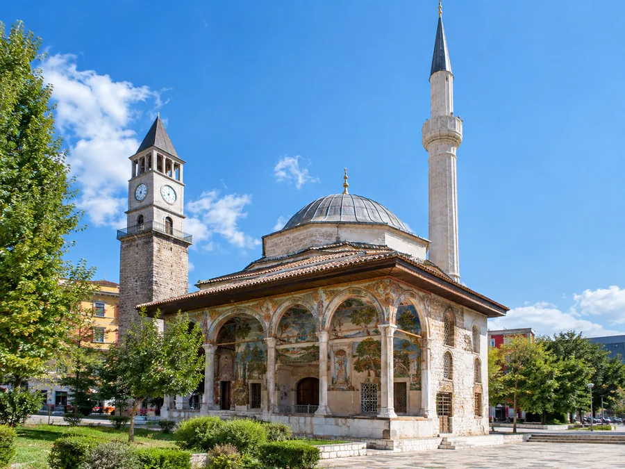 Xhamia e Et'hem Beut me portikun e pikturuar dhe minaren e hollë, me Kullën e Sahatit pas saj